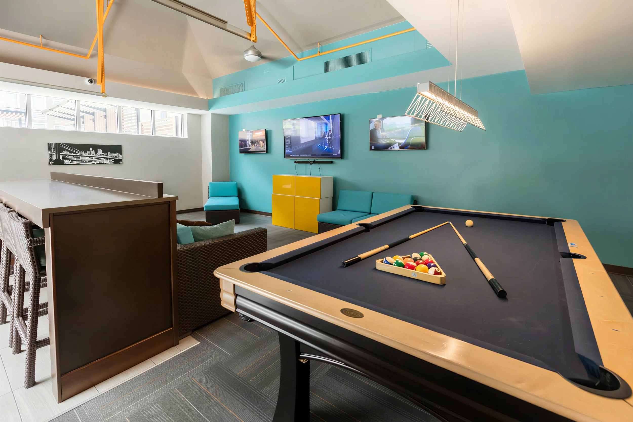 Resident game room with pool table, televisions and lounge seating at 300 East 17th Apartments